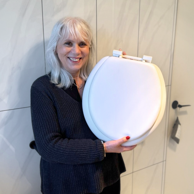 An elderly person holding a Cush'n Soft padded toilet seat